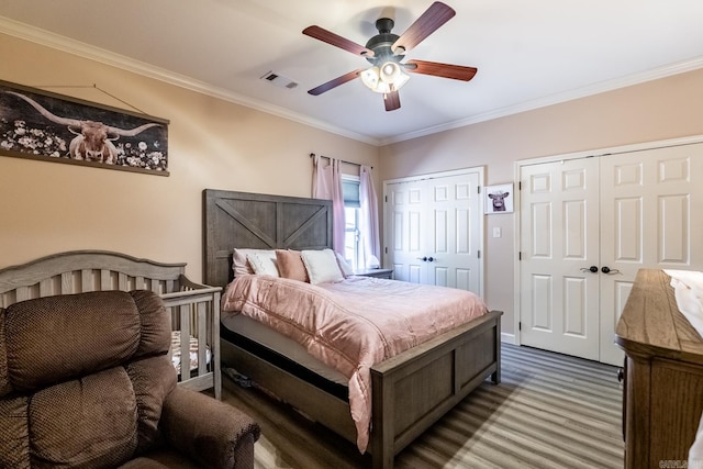 carpeted bedroom with visible vents, ceiling fan, crown molding, and multiple closets