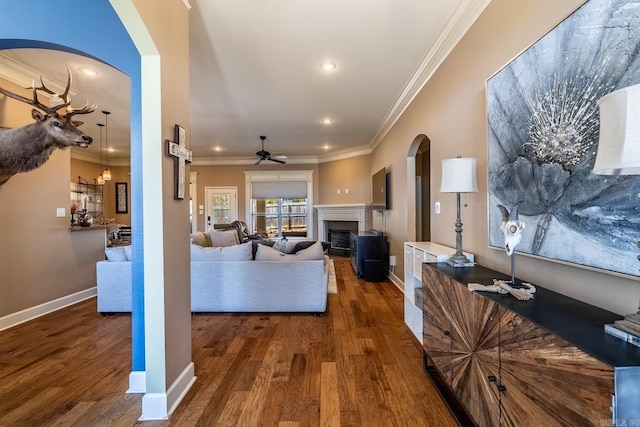 living room featuring arched walkways, crown molding, ceiling fan, and wood finished floors