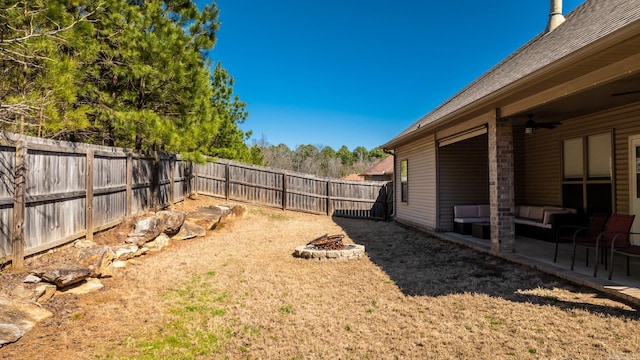 view of yard with ceiling fan, a patio, an outdoor fire pit, and a fenced backyard