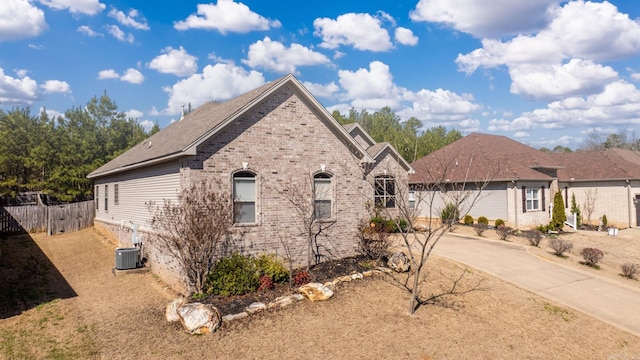 view of home's exterior featuring concrete driveway, cooling unit, fence, and brick siding