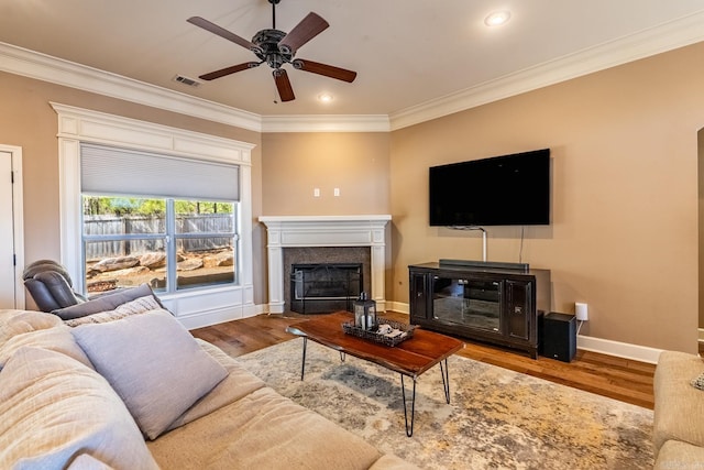 living area featuring visible vents, a ceiling fan, wood finished floors, crown molding, and baseboards