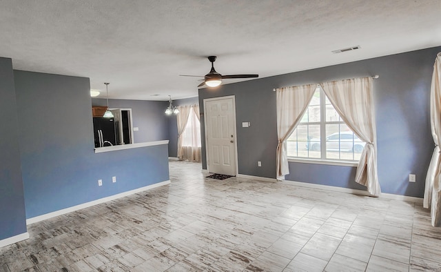 unfurnished living room featuring a textured ceiling, baseboards, visible vents, and ceiling fan