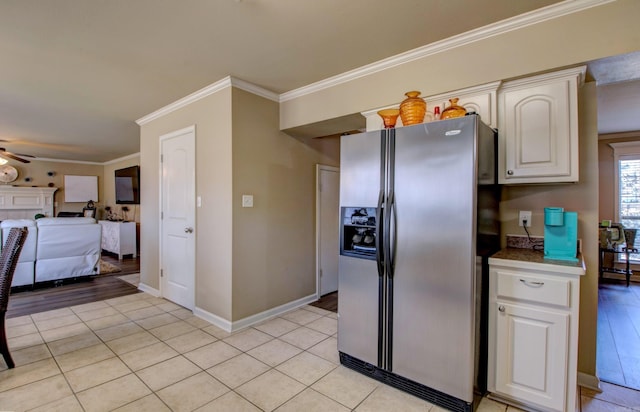 kitchen featuring light tile patterned floors, stainless steel fridge with ice dispenser, ornamental molding, ceiling fan, and white cabinets