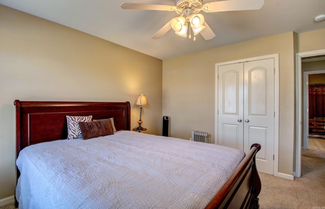 bedroom with radiator, baseboards, light carpet, a closet, and a ceiling fan