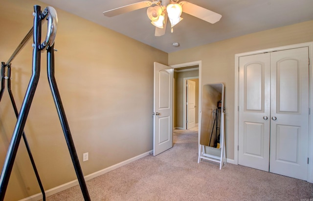 unfurnished bedroom featuring light carpet, ceiling fan, a closet, and baseboards