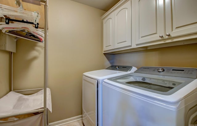 washroom with cabinet space, independent washer and dryer, baseboards, and light tile patterned flooring