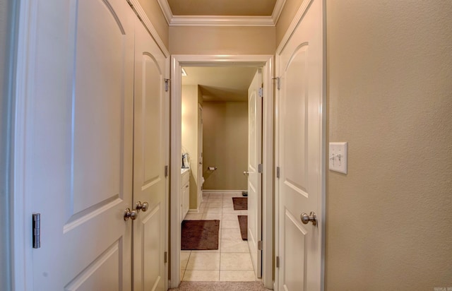 corridor featuring light tile patterned floors, a textured wall, baseboards, and ornamental molding