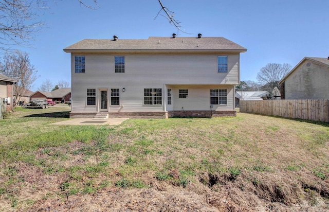 rear view of property featuring entry steps, a yard, and fence