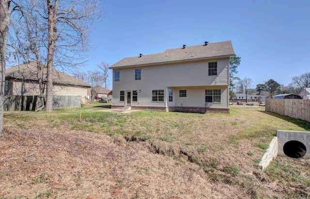 rear view of house with entry steps, a patio, a yard, and fence