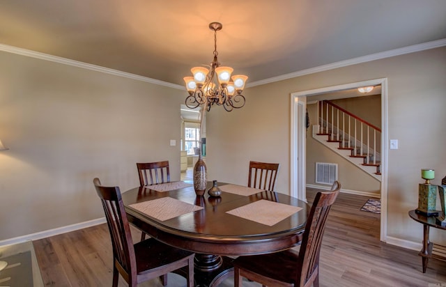 dining room with a chandelier, ornamental molding, baseboards, and wood finished floors