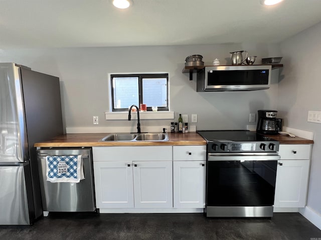 kitchen featuring a sink, wood counters, finished concrete flooring, white cabinetry, and appliances with stainless steel finishes