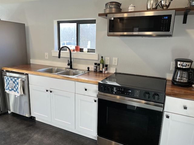 kitchen featuring a sink, butcher block countertops, white cabinetry, and stainless steel appliances