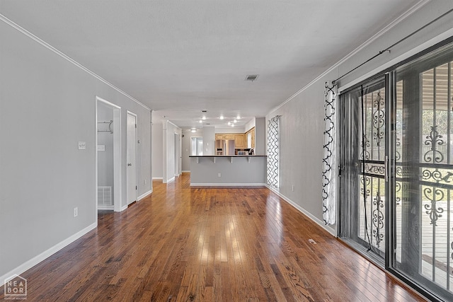 unfurnished living room with visible vents, ornamental molding, baseboards, and hardwood / wood-style flooring