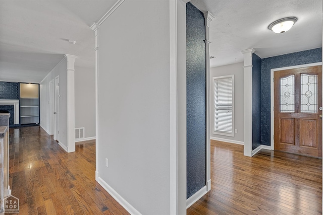 foyer with visible vents, baseboards, decorative columns, a fireplace, and wood-type flooring