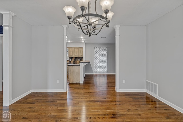 unfurnished dining area with a notable chandelier, wood finished floors, visible vents, and baseboards