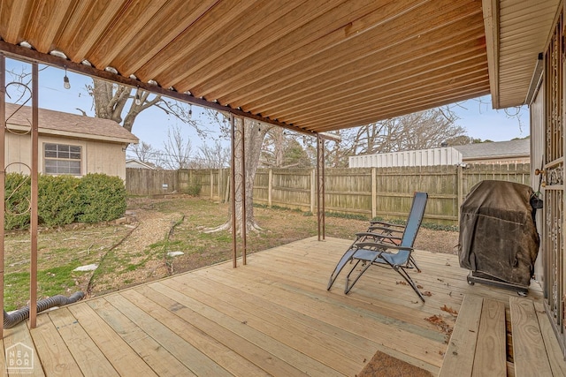 wooden terrace with grilling area and a fenced backyard