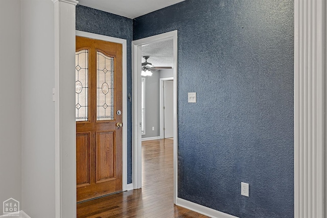 entrance foyer with baseboards, ceiling fan, a textured wall, dark wood-style floors, and a textured ceiling