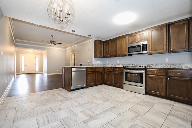 kitchen featuring decorative light fixtures, stainless steel appliances, ornamental molding, and ceiling fan with notable chandelier