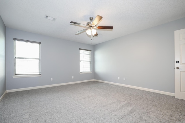 spare room with visible vents, a textured ceiling, baseboards, and a ceiling fan