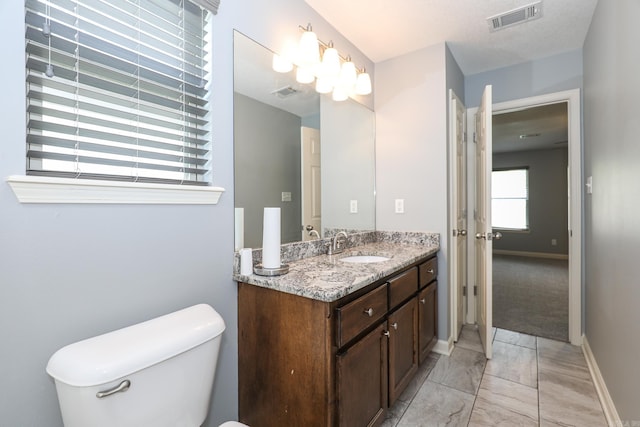 bathroom featuring vanity, toilet, baseboards, and visible vents