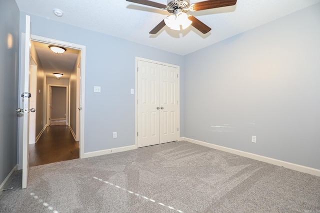 unfurnished bedroom with ceiling fan, carpet, a closet, and baseboards