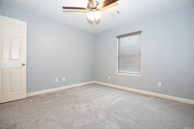 empty room with baseboards, visible vents, a ceiling fan, and carpet