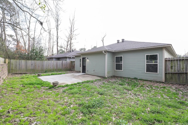 back of property featuring a lawn, roof with shingles, a fenced backyard, and a patio area