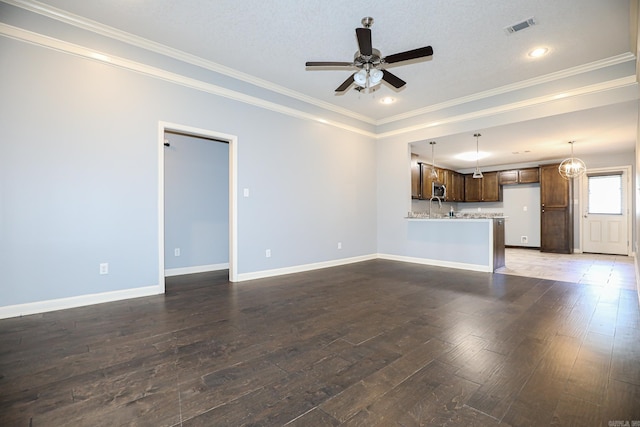 unfurnished living room featuring visible vents, crown molding, baseboards, ceiling fan, and wood finished floors