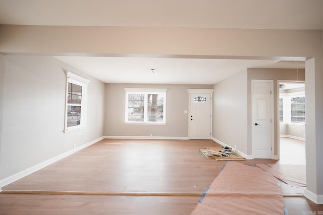 foyer entrance with a wealth of natural light, baseboards, and wood finished floors