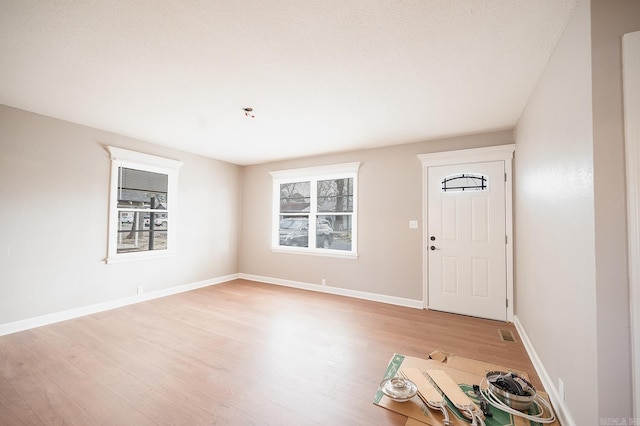 foyer entrance featuring visible vents, baseboards, and light wood finished floors