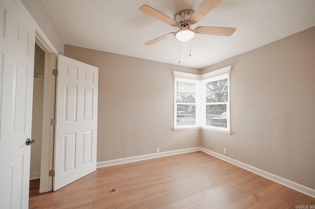 empty room featuring light wood-type flooring, baseboards, and a ceiling fan