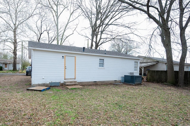 rear view of property featuring a lawn, entry steps, fence, cooling unit, and crawl space