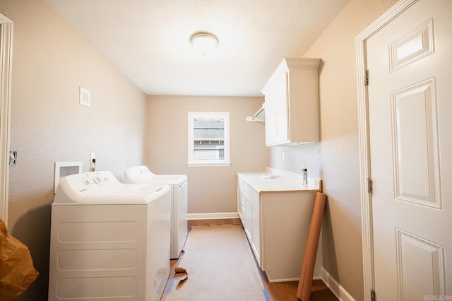 washroom featuring baseboards, cabinet space, and washing machine and dryer