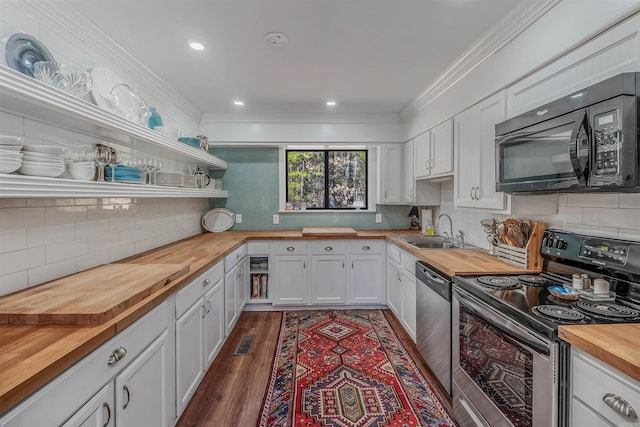 kitchen with a sink, butcher block countertops, ornamental molding, stainless steel appliances, and open shelves