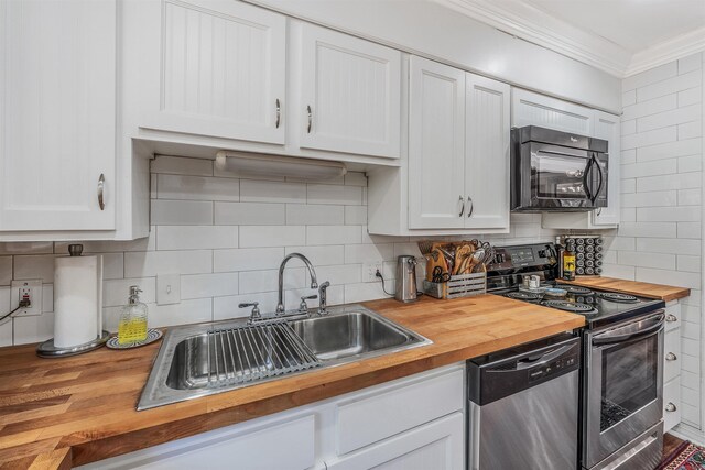 kitchen featuring butcher block countertops, appliances with stainless steel finishes, crown molding, and a sink