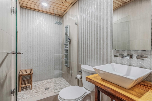 bathroom featuring a sink, toilet, wood ceiling, and tiled shower