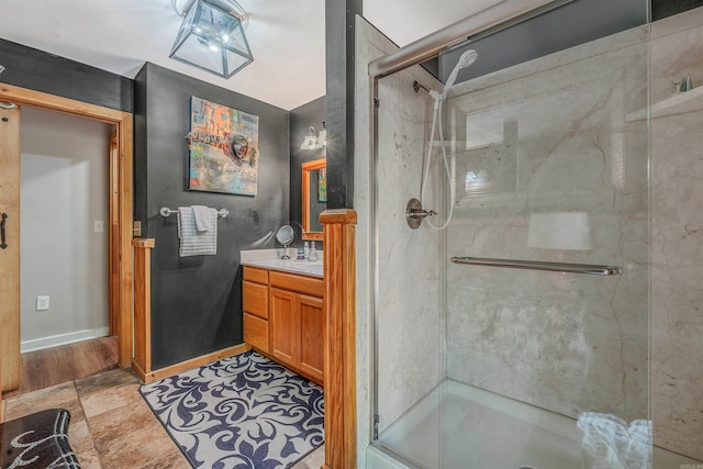 bathroom with baseboards, vanity, and a shower stall