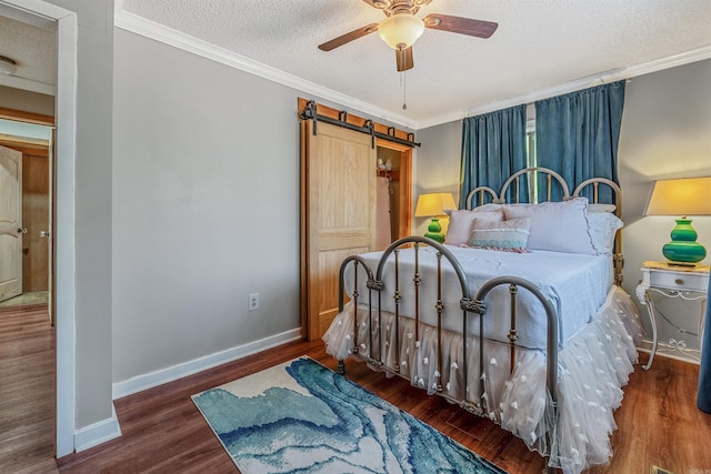 bedroom with wood finished floors, baseboards, crown molding, a textured ceiling, and a barn door