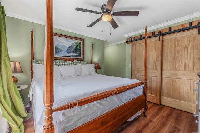 bedroom featuring a barn door, wood finished floors, a ceiling fan, and ornamental molding