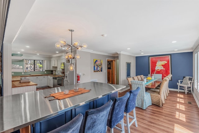 interior space with baseboards, light wood finished floors, an inviting chandelier, recessed lighting, and crown molding