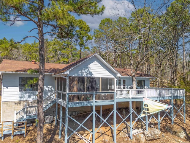 rear view of house with a shingled roof, stairs, and a sunroom