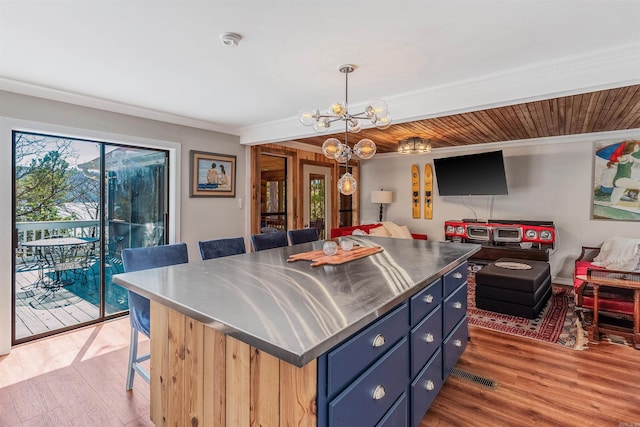 kitchen with open floor plan, a healthy amount of sunlight, stainless steel countertops, and wood finished floors