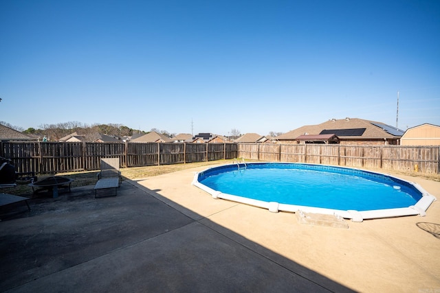 view of swimming pool featuring a fenced backyard, a residential view, a fire pit, a fenced in pool, and a patio area