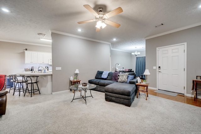 living room with baseboards, visible vents, a textured ceiling, crown molding, and ceiling fan with notable chandelier