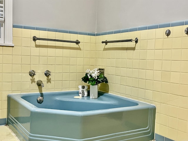 full bath featuring tile walls and a bath