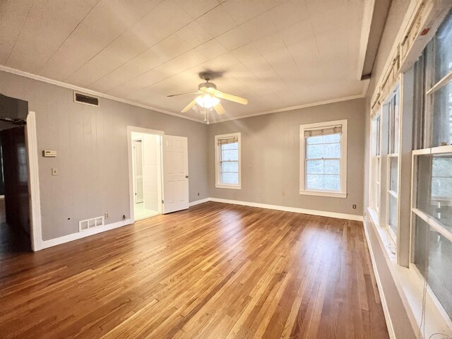 unfurnished room featuring baseboards, wood finished floors, visible vents, and ceiling fan