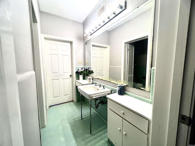 bathroom with a sink, visible vents, and ornamental molding