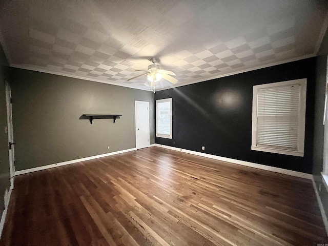 spare room with ornamental molding, wood finished floors, baseboards, and ceiling fan