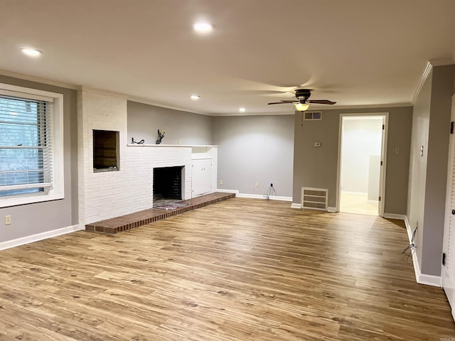 unfurnished living room featuring visible vents, a brick fireplace, wood finished floors, and crown molding