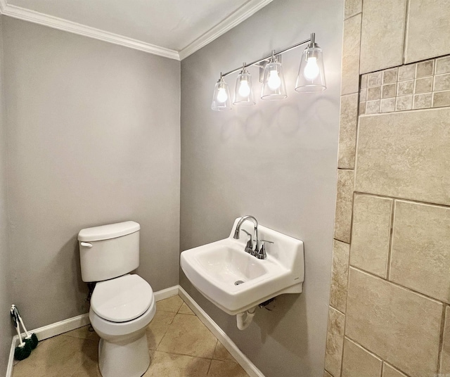 half bathroom featuring tile patterned floors, toilet, a sink, crown molding, and baseboards